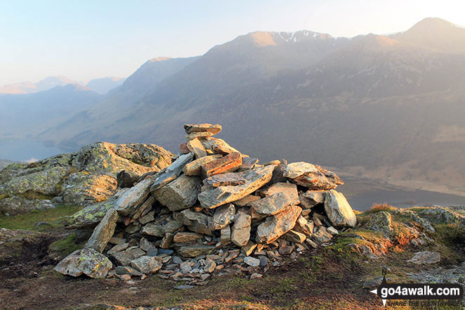 The setting sun on the cairn on the summit of Rannerdale Knotts