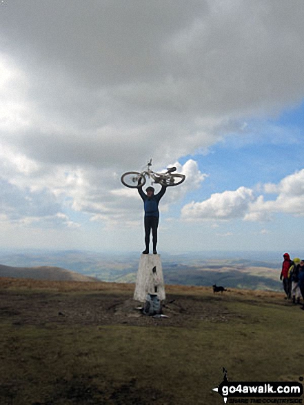 Cyclist (and bike) on The Calf trig point