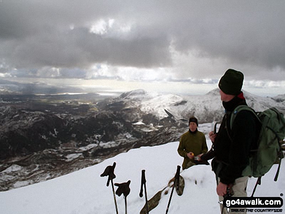 Walk gw117 Snowdon and Yr Aran via The Watkin Path from Bathania, Nantgwynant - Friends on the summit of Yr Aran in the snow with Beddgelert below (left centre) and Moel Hebog on the horizon (right)