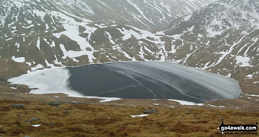 Walk c220 Helvellyn via Striding Edge from Glenridding - A frozen Grisedale Tarn from the lower slopes of Dollywaggon Pike in the snow