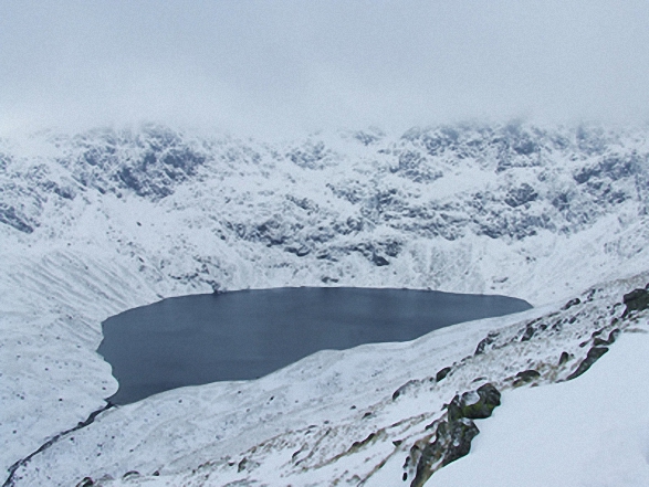 Blea Water with mist still shrouding High Street beyond from Rough Crag (Riggindale) summit in the snow