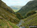 Looking down Styhead Gill from Sty Head to a sunlit Borrowdale  with Bleaberry Fell the high point in the distance